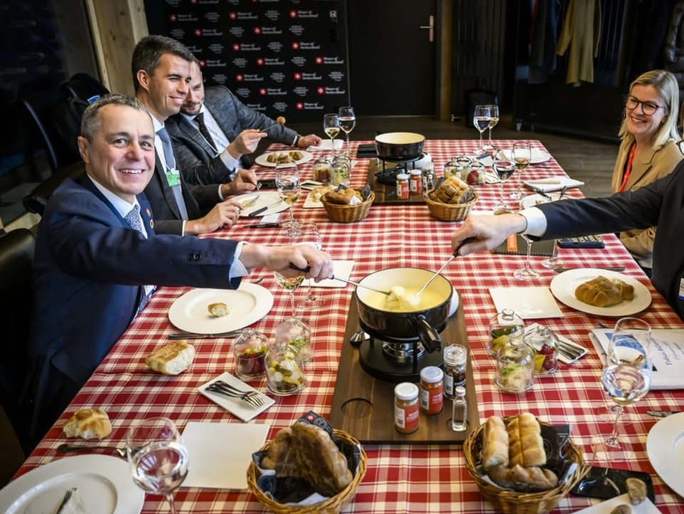 Cassis mit anderen Personen an einem Tisch, sie essen Fondue, Cassis lacht in die Kamera