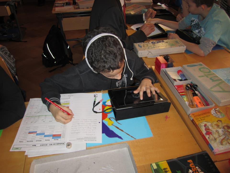 Ein Junge mit weissen Kopfhörern schreibt einen Text.