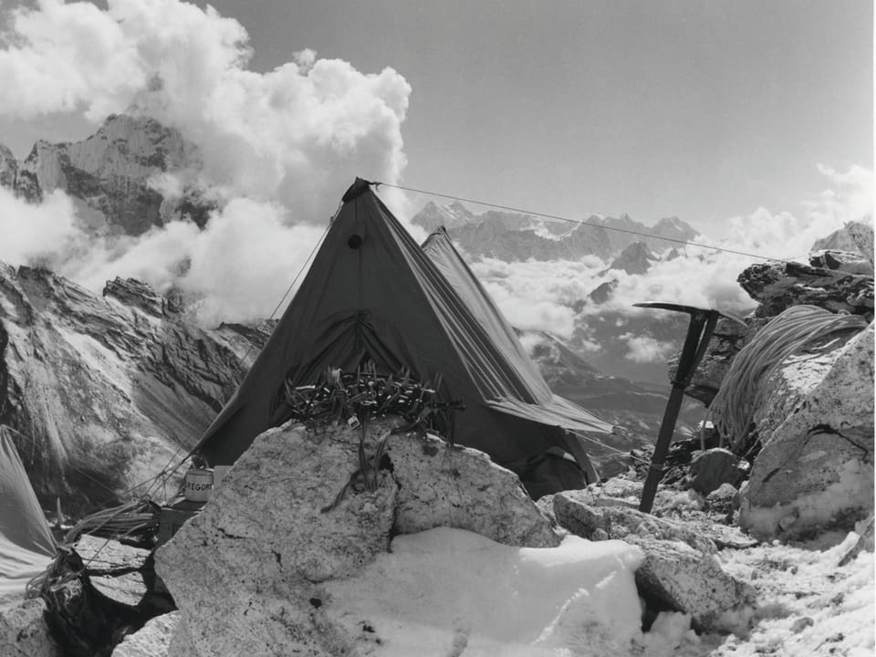 Ein kleines Zelt steht auf einem Felsvorsprung. Dahinter liegt der majestätische Horizont des Himalaya.