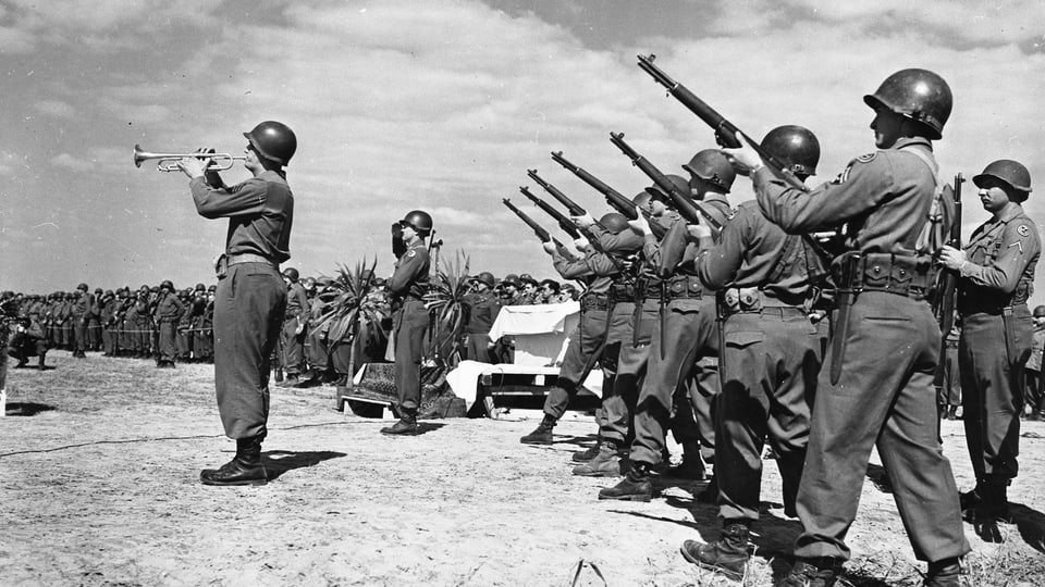 Soldaten mit Gewehren im 2. Weltkrieg. Davor ein Soldat der Trompete spielt.
