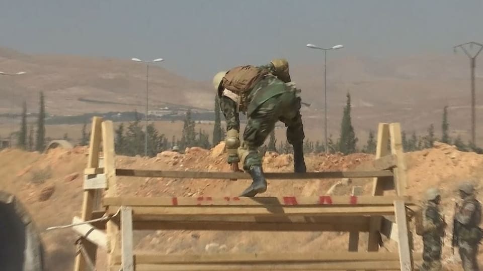 Soldat springt über ein Hindernis. Im Hintergrund wüstenähnliche Landschaft.