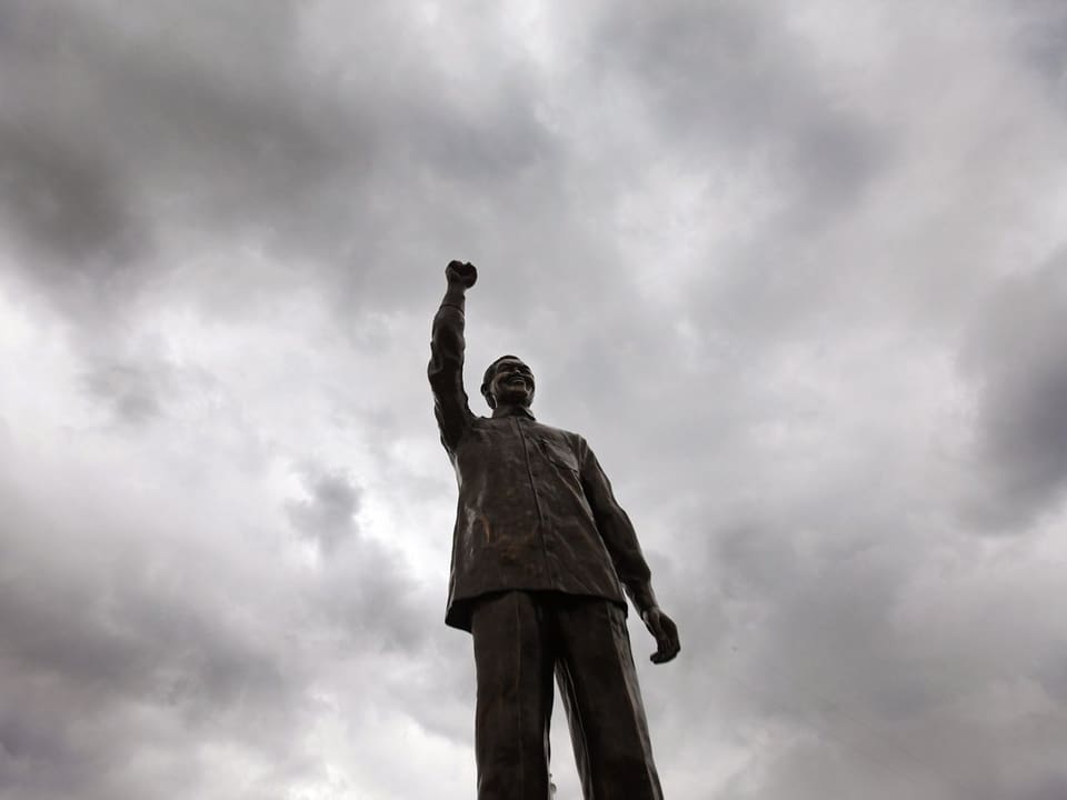 Statue von Nelson Mandela ragt in den dunkelgrauen Himmel