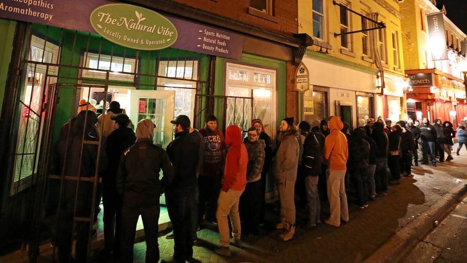 Menschen stehen Schlange vor einem Cannabis-Laden.