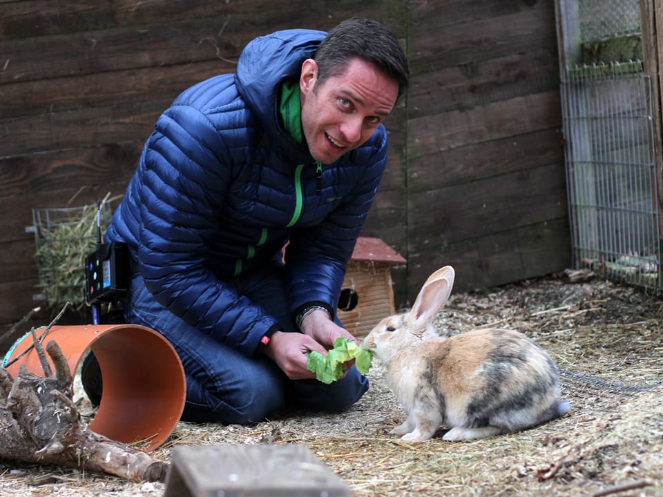Adrian Küpfer füttert einem Kaninchen ein Salatblatt.