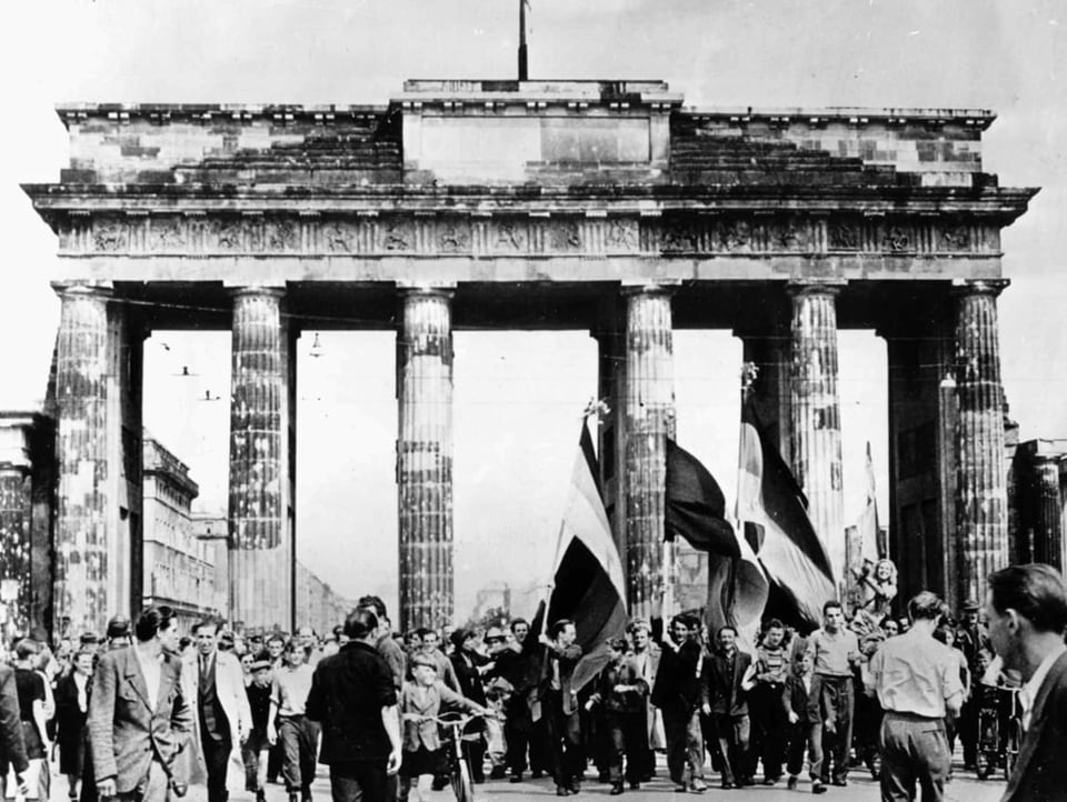 Schwarzweiss-Bild: Unzählige Menschen gehen durchs Brandenburger Tor.