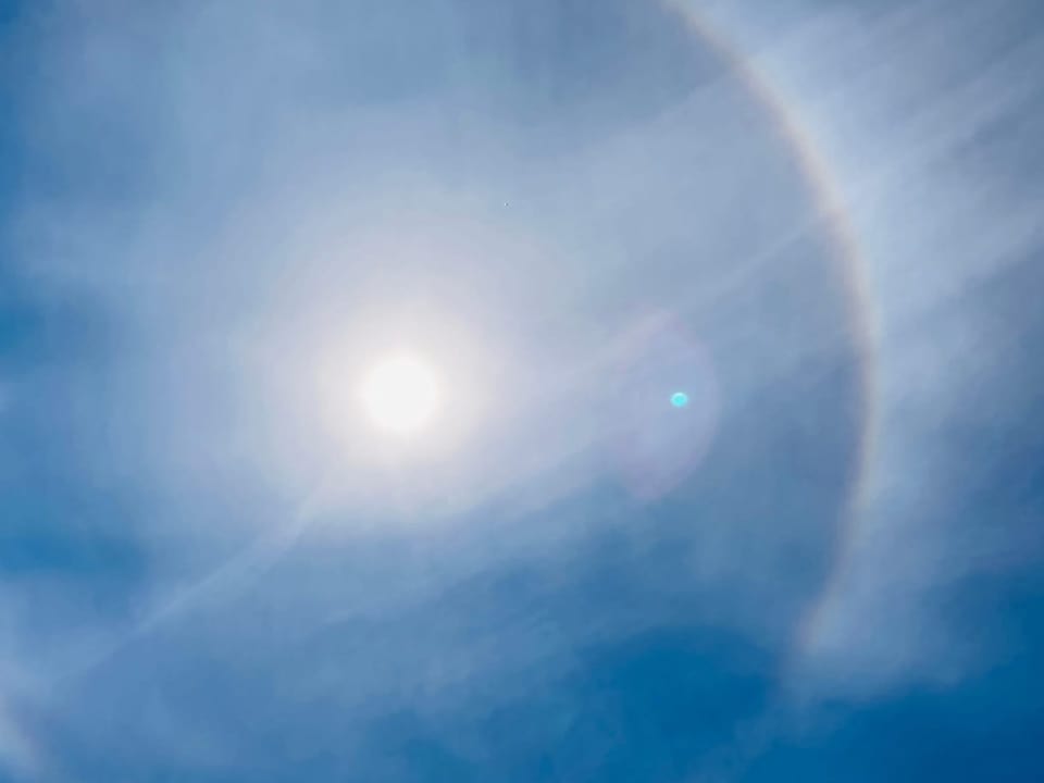 Regenbogen-Ring um die Sonne am milchigen Himmel