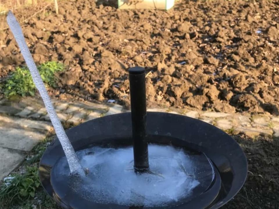 Ein Gefäss mit gefrorenem Wasser, aus dem ein Eiszapfen ragt.