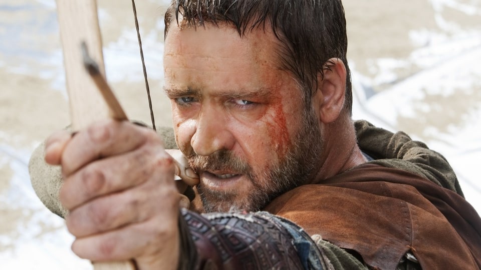 Russell Crowe zielt in seiner Rolle als Robin Hood mit grimmiger Miene direkt auf die Kamera.