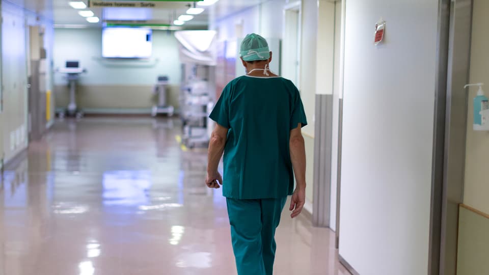 Arzt läuft durch einen Gang im Spital