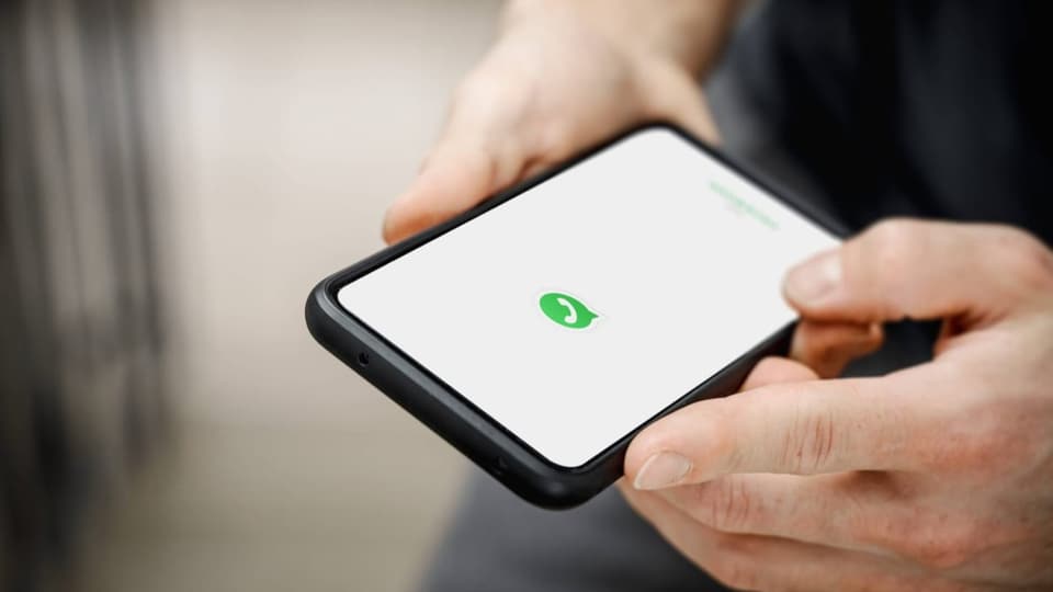 Mann hält ein Smartphone in der Hand und öffnet WhatsApp.