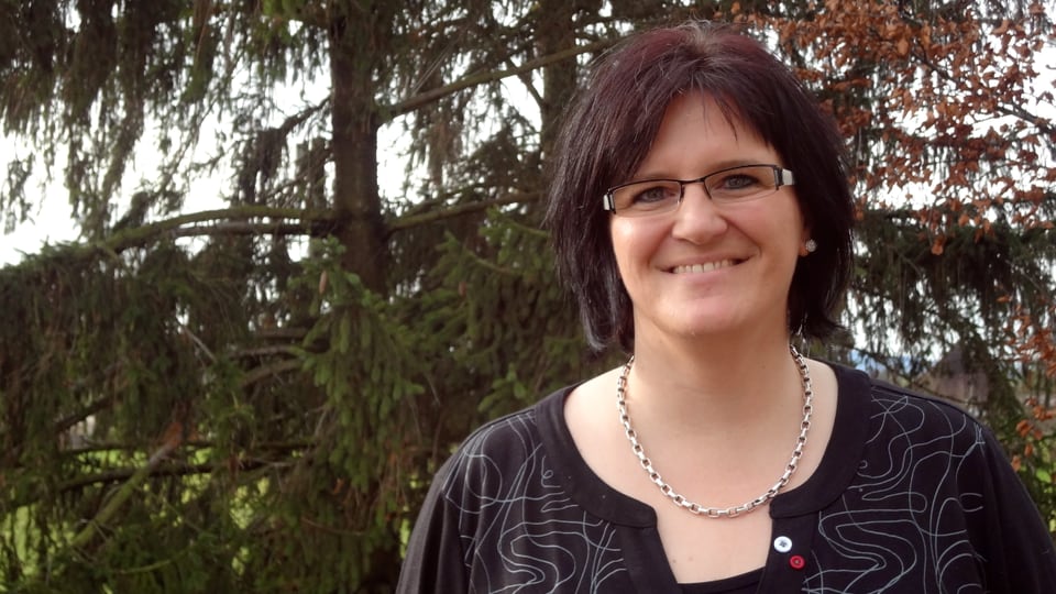 Karin Boss-Röthlisberger Porträt von Karin Boss-Röthlisberger im Freien vor einem Tannenbaum. Karin Boss-Röthlisberger hat dunkle, knapp schulterlange Haare und trägt eine Brille.