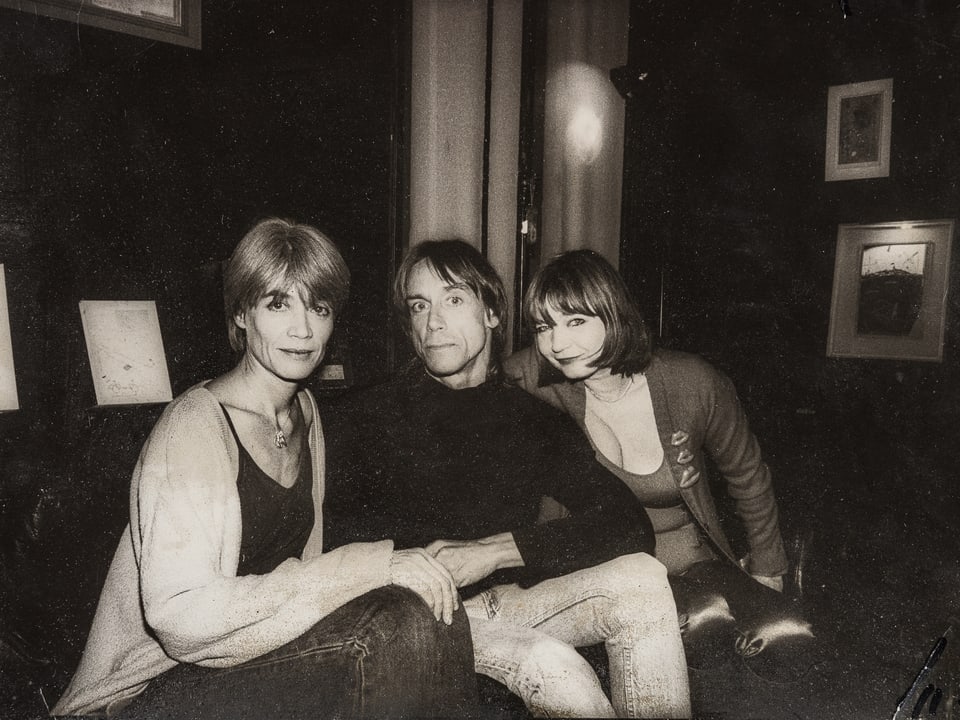 Schwarz-Weiss-Foto: Zwei Frauen und ein Mann sitzen nebeneinander und schauen in die Kamera. 