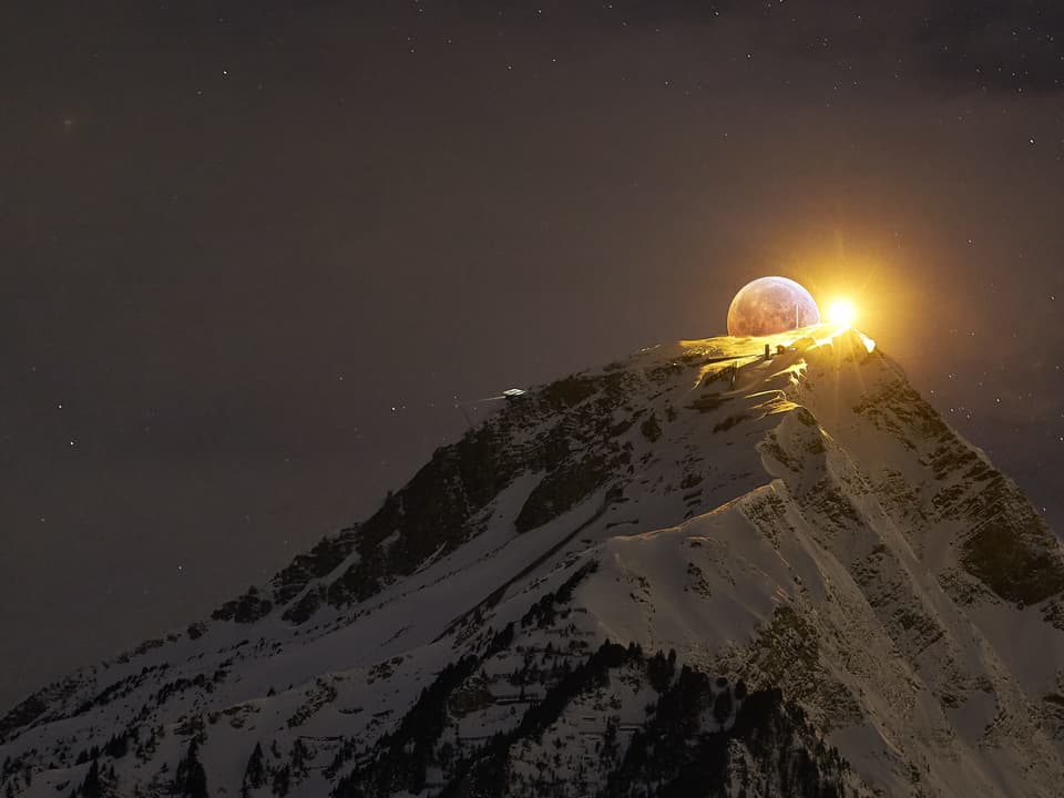 Der Mond geht hinter einem Berg auf.