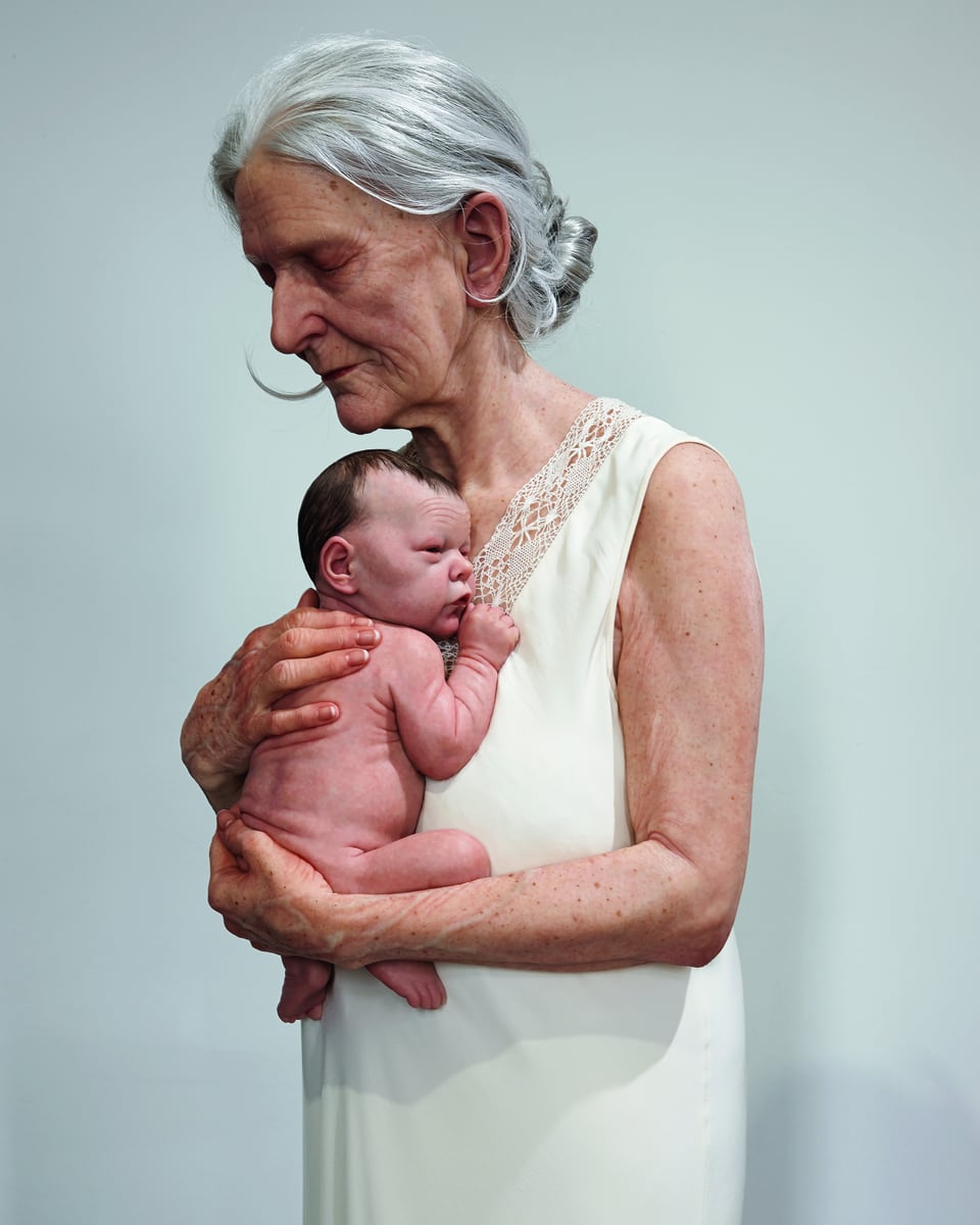 alte Frau, leicht seitlich nach links, hält ein Baby im Arm, ihre Augen geschlossen, Kopf leicht geneigt.