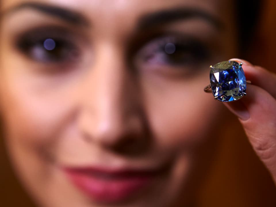 Frau hält Diamantring vor Gesicht