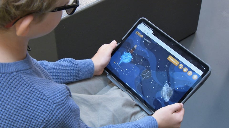 Ein Kind betrachtet die App «Kidimo» auf einerm Tablet-Computer.