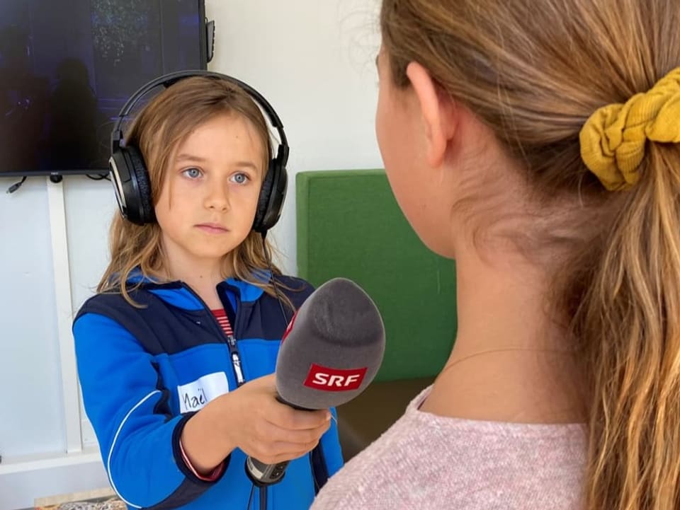 Ein Kinderreporter interviet ein Mädchen mit dem SRF Mikrofon