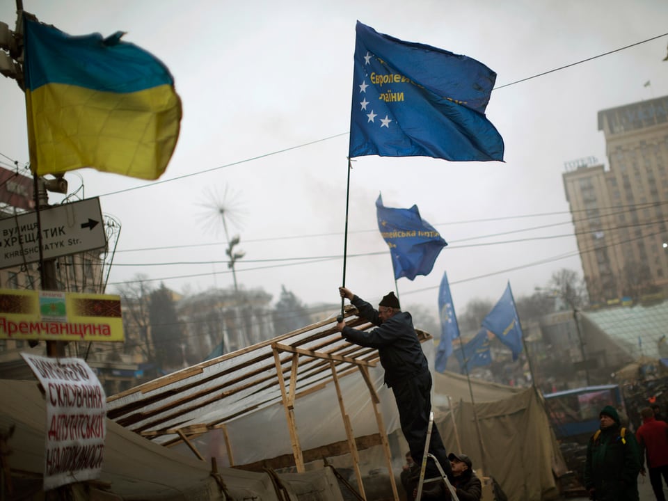 Ein Mann hisst auf dem Unabhängigkeitsplatz die europäische Flagge neben der ukrainischen.