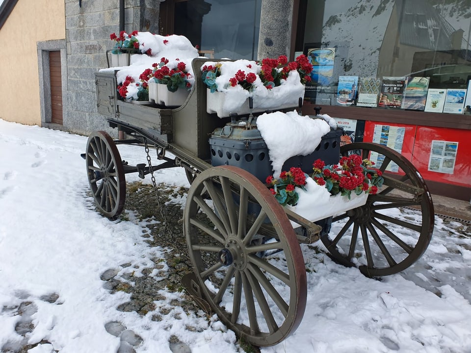 Alte Kutsche mit Blumen und Schnee, am Boden ebenfalls Schnee.