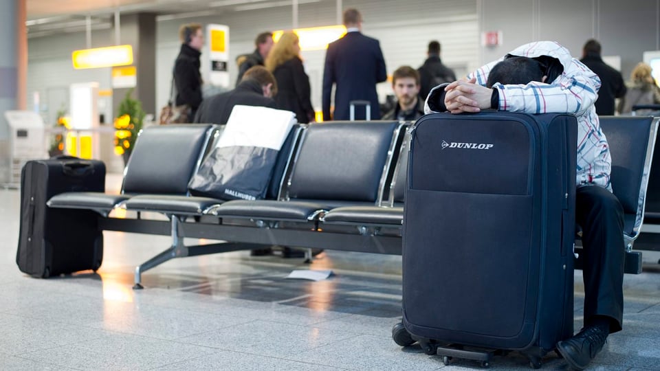 Sitzender Mann hat Kopf auf Koffer gelegt.