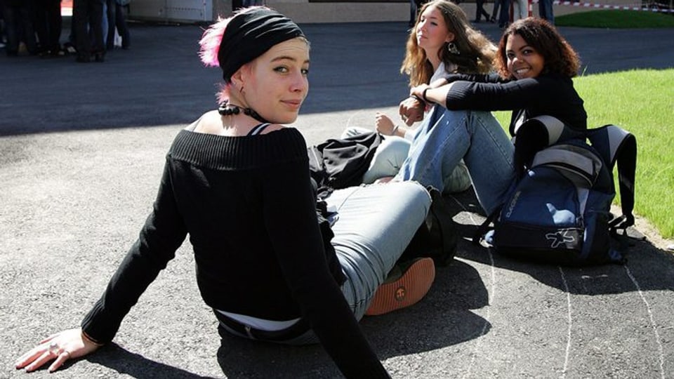 Junge Frauen sitzen auf dem Pausenplatz