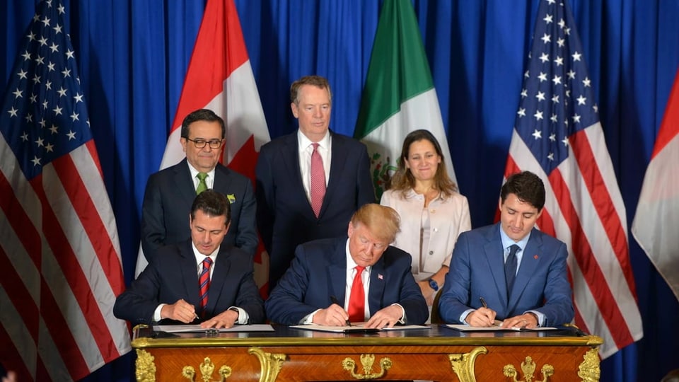 Unterzeichnung eines Abkommens, sechs Personen, Fahnen im Hintergrund