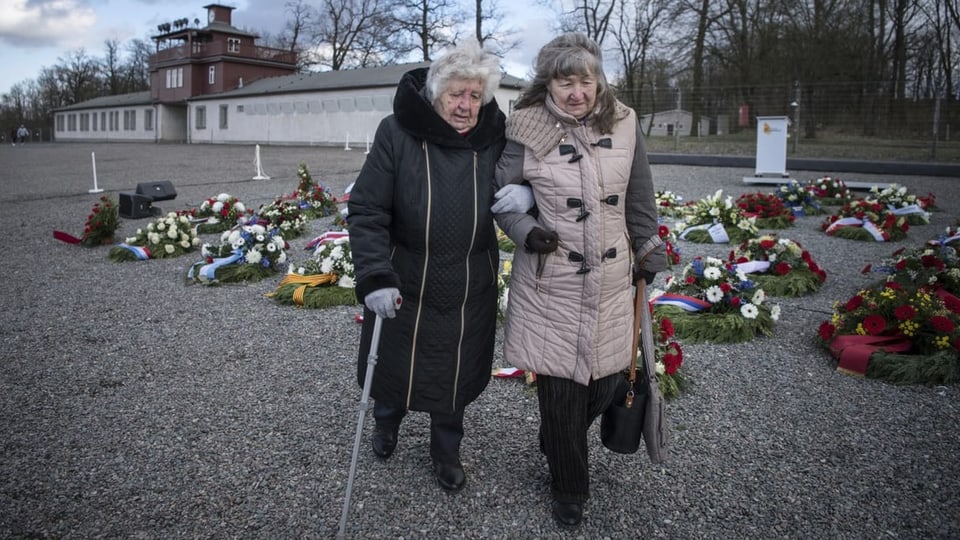 Anastasia Gulej und ihre Tochter Walentyna Gulej laufen an Blumenkränzen vorbei.