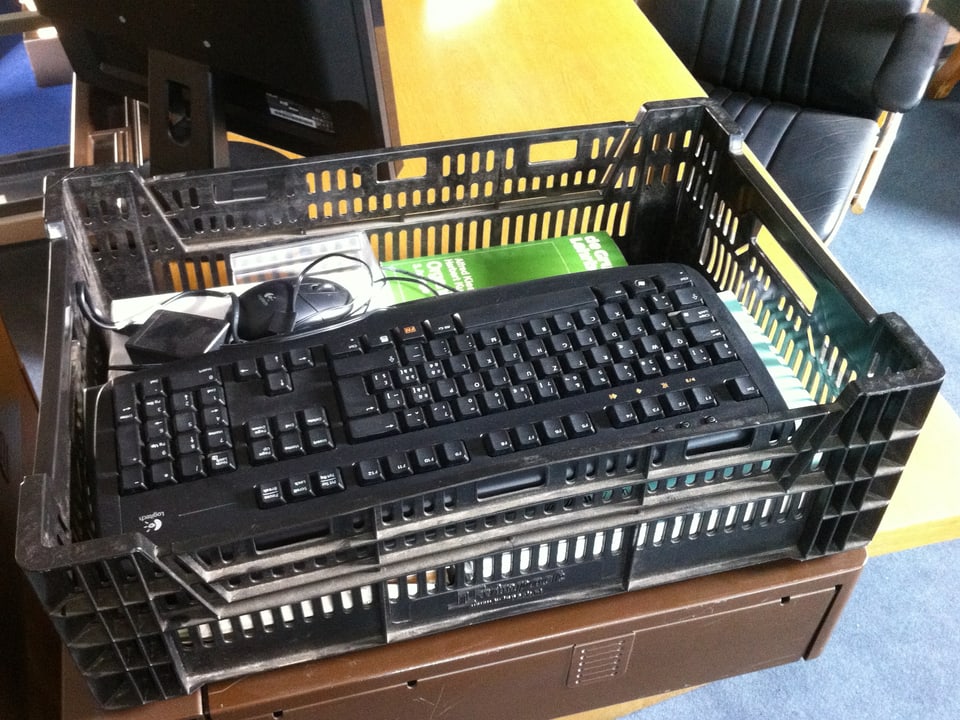 Eine Zügelkiste aus Plastik mit einer Computertastatur, einer Maus und anderen Gegenständen.