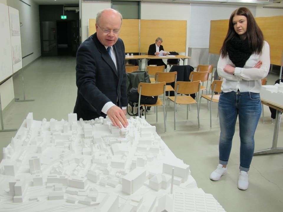 Gemeindepräsident Stephan Rawyler erklärt einer Journalistin das Modell des Neuhauser Zentrums.