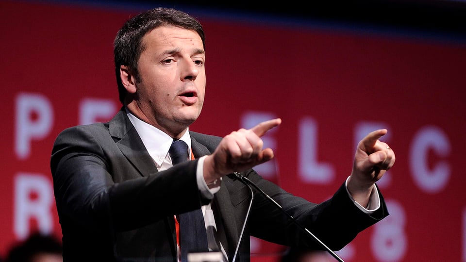 Renzi auf einem Podium: er gestikuliert und benutzt dabei beide Arme. 