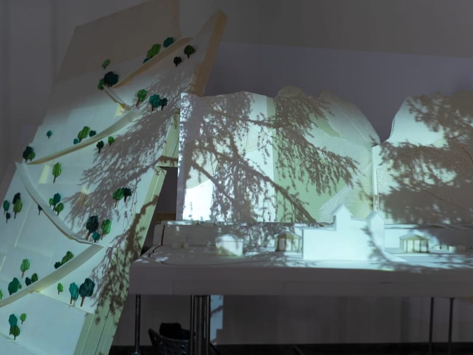 Weisses Architektur-Modell mit kleinen Bäumchen und einer Baum-Projektion drauf