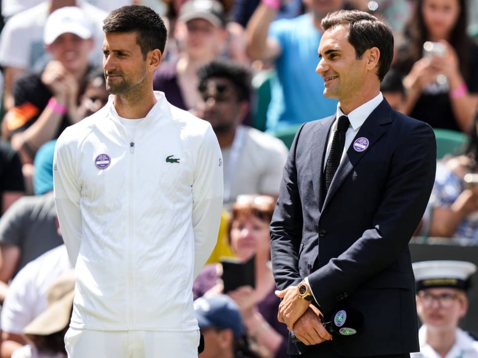 Werden Teamkollegen Novak Djokovic und Roger Federer stehen gemeinsam auf dem Tennisplatz.