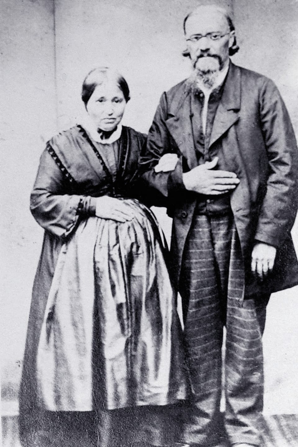 Historische Fotografie in schwarz-weiss von einem Ehepaar, das Arm in Arm vor der Kamera steht.