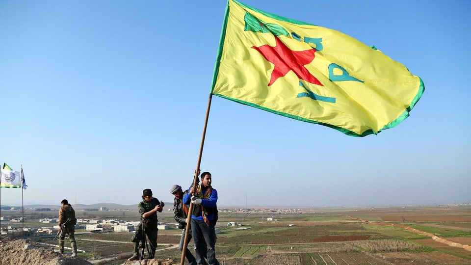 Kurdische Kämpfer hissen eine Fahne bei Kobane