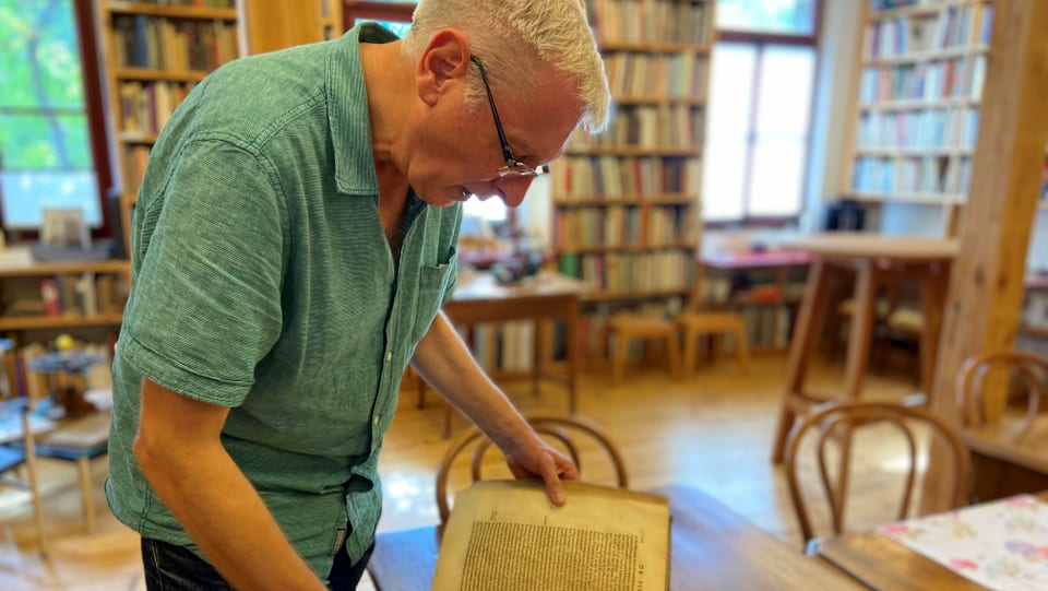 Antiquar Gerhard Becker blättert in der Buchhandlung in seinem Lieblingsbuch.