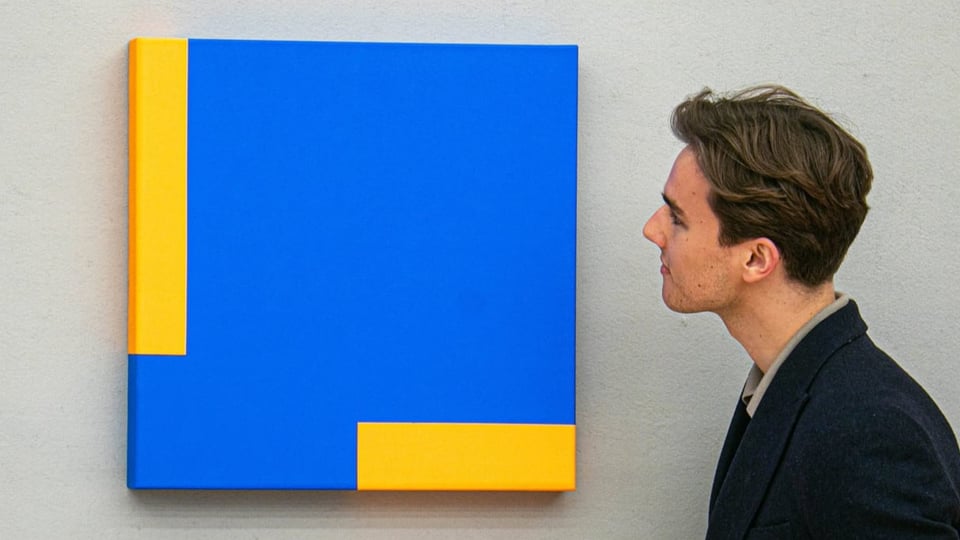 Mann schaut ein quadratisches Bild mit eckigen, blauen und glebven Flächen an