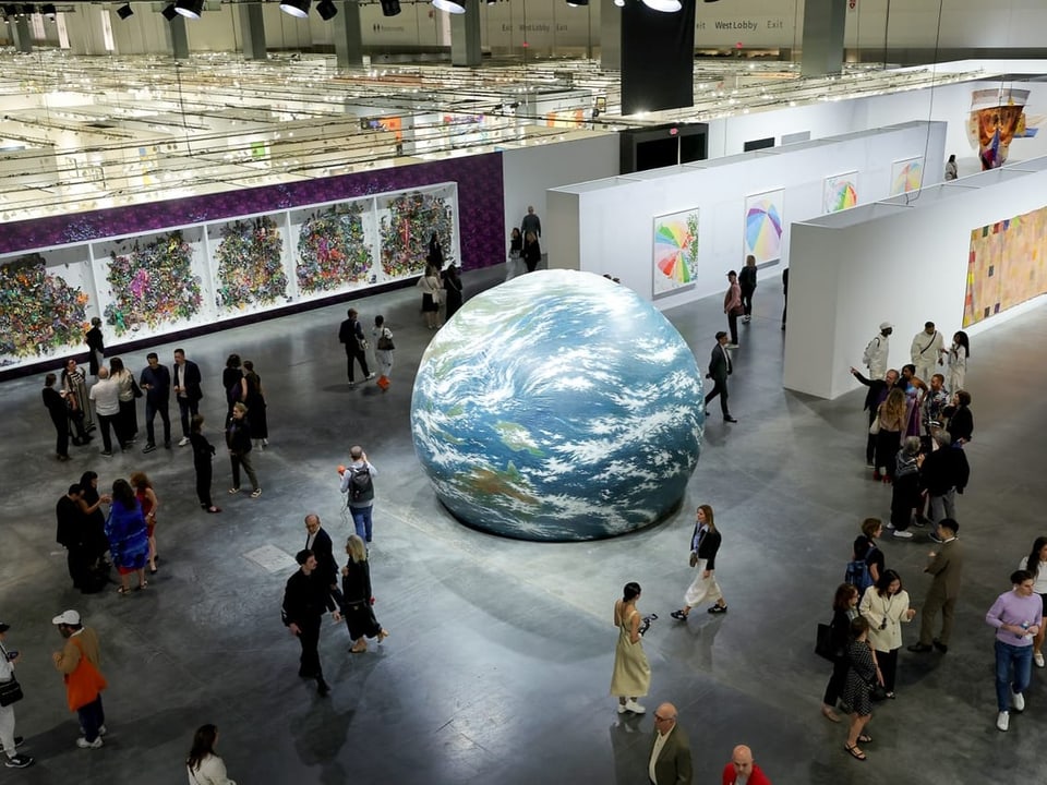 In einer grossen Galerie stehen Menschen um einen aufgeblasenen Globus. 