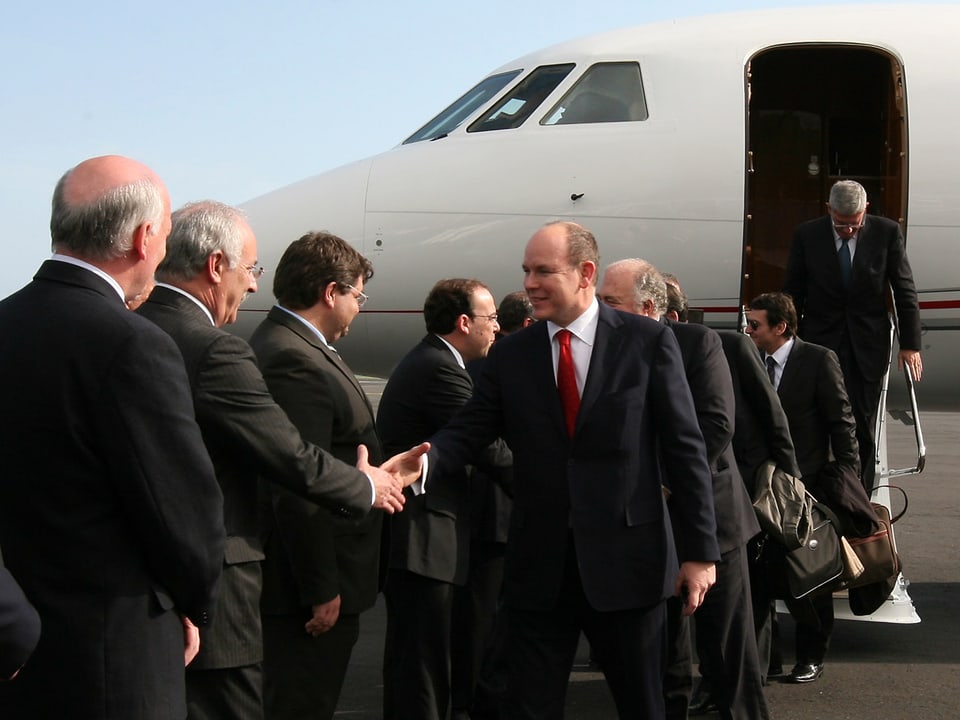 Fürst Albert von Monaco mit anderen Personen vor einem Jet.