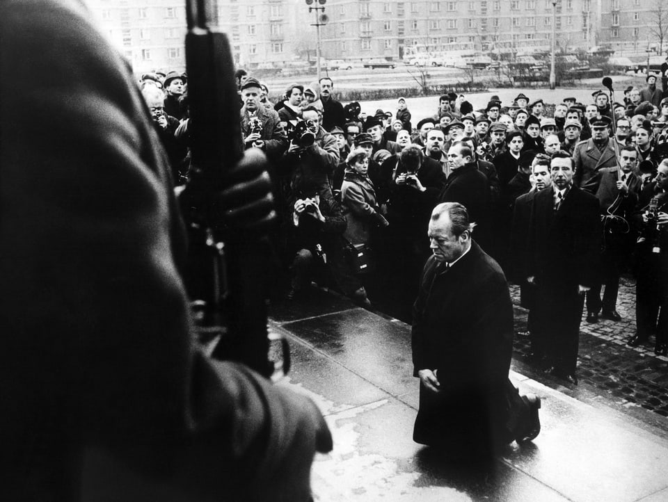 Schwarzweissbild, Willy Brandt kniet in Polen vor dem Ehrenmal der Toten des Warschauer Ghettos nieder.