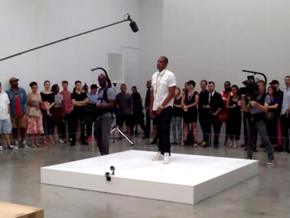 Bei einem Videodreh steht Rapper Jay-Z im New Yorker Museum of Modern Art auf einem weissen Podium, umringt von Zuschauern.