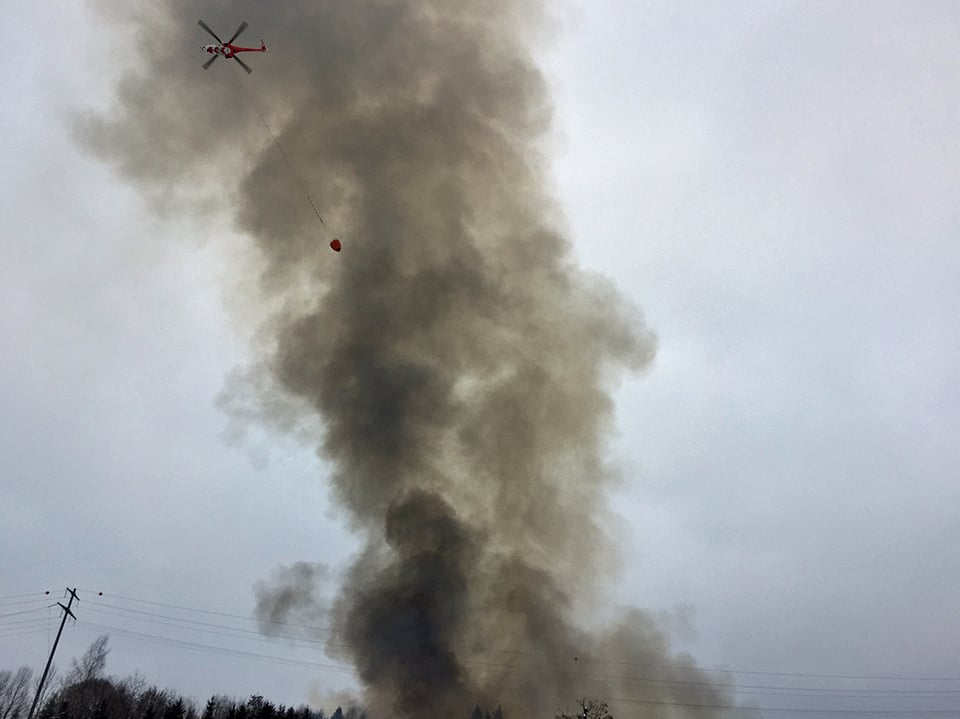 Helikopter über einer schwarzen Rauchsäule.