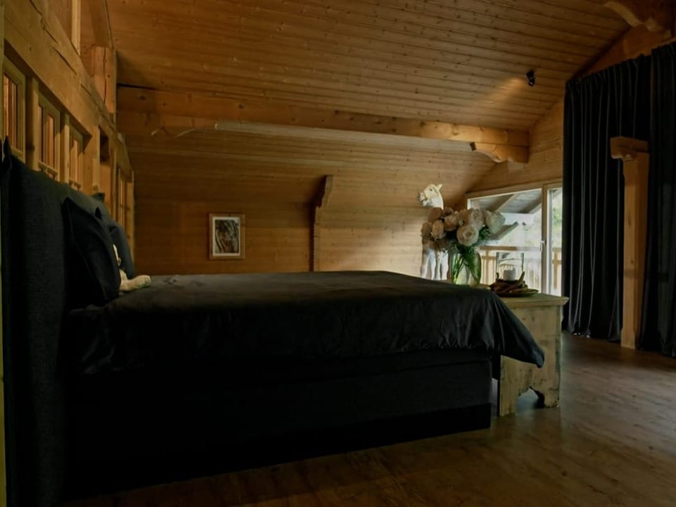 Ein schwarzes Bett in einem Holz verkleideten Zimmer.