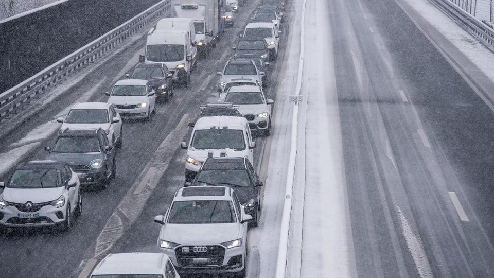 Viele Autos stehen auf der Autobahn im Stau während es schneit.