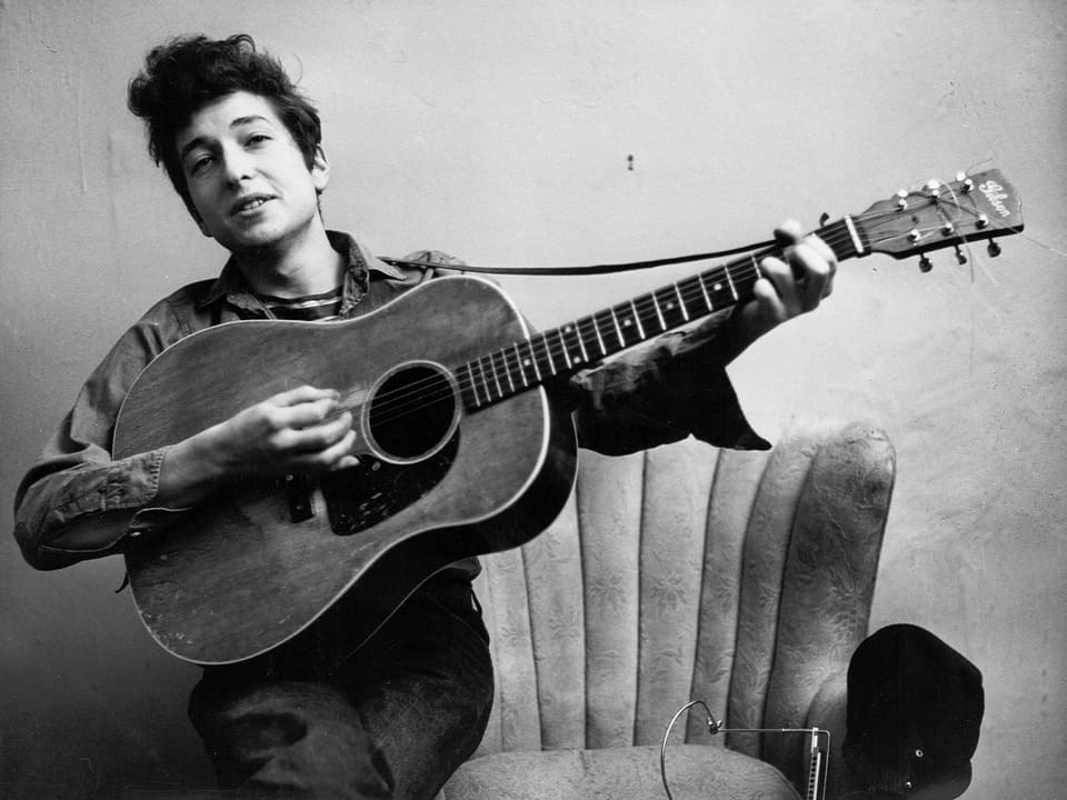 Ein Porträt von Bob Dylan mit Gitarre in der Hand.