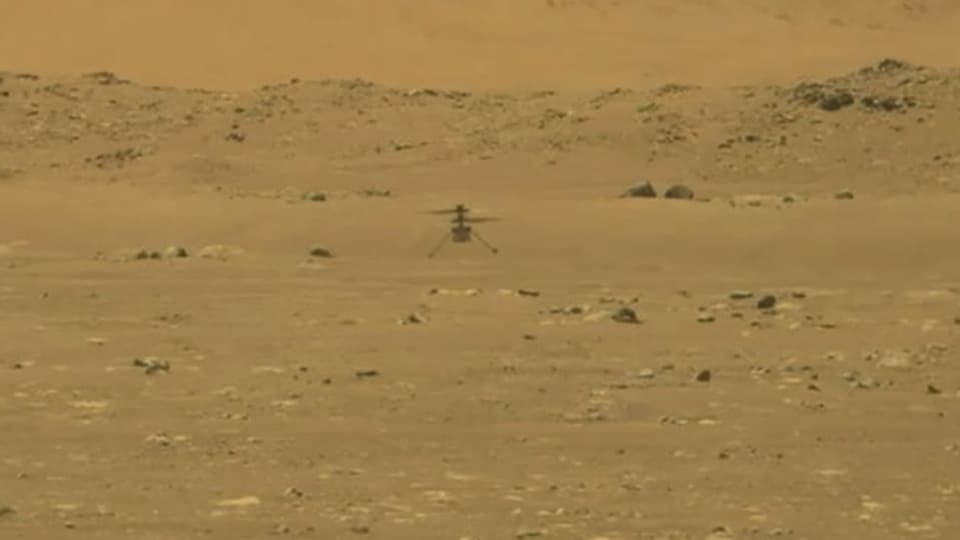Ein Helikopter schwebt über der Marsoberfläche.