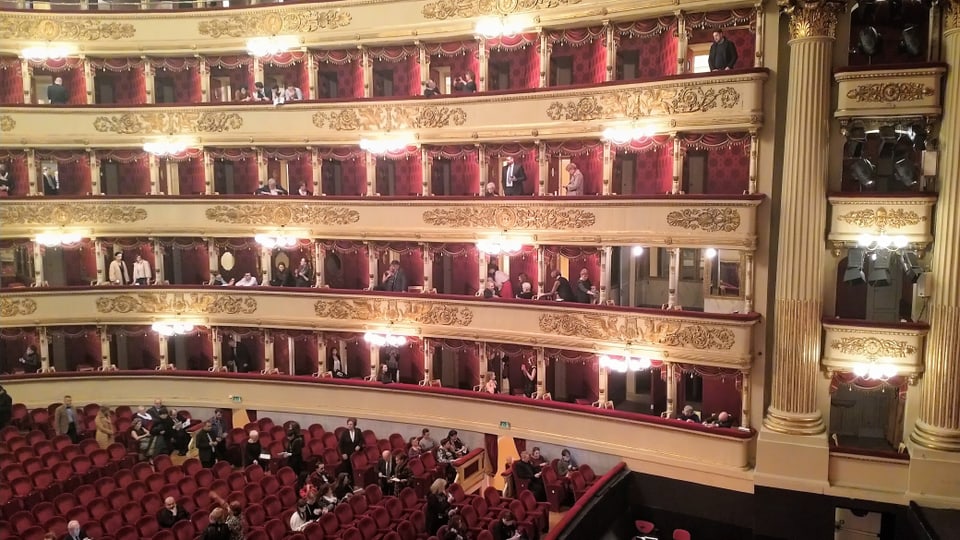 Mnecshen machen sich in einem rieseigen gold-roten pompösen Saal beriet für eine Theaterauffürung.
