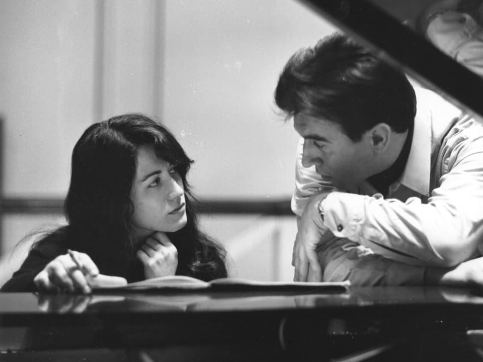 Ein Mann und eine Frau sitzen am Klavier und diskutieren miteinander.
