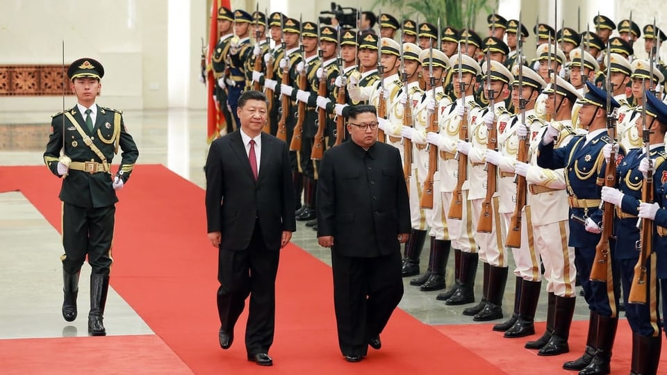 Xi und Kim eine Ehrengarde abschreitend.