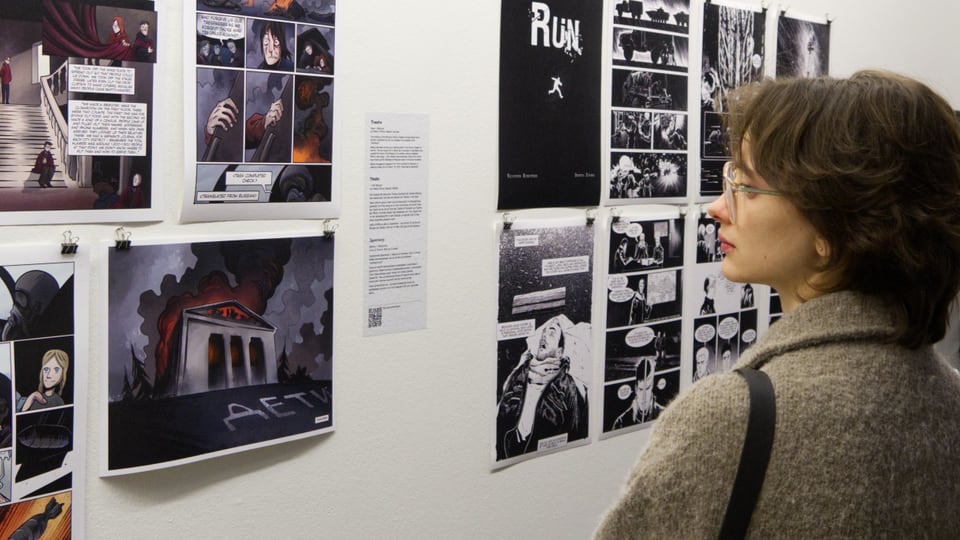 Eine Frau schaut auf ein Bild einer Comicausstellung