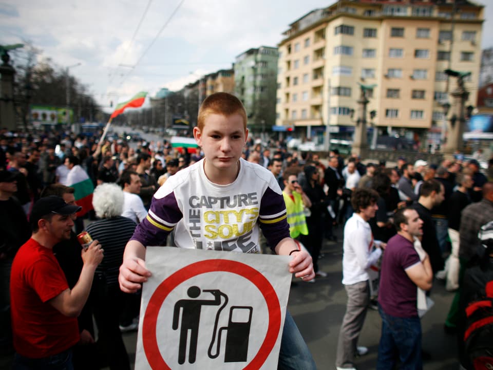 Ein Junge hät an einer Demonstration ein Transparent in die Höhe.